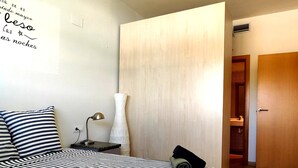 Une chambre à coucher avec un lit, une table de chevet, une lampe et un grand vase.