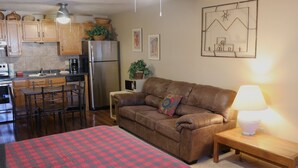 A compact living space with a kitchenette, a sofa, a dining table, and a bed.