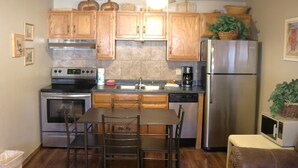 A kitchen with wooden cabinets, stainless steel appliances, a dining table with chairs, and a ceiling fan.