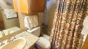 A bathroom with a sink, mirror, towel rack, toilet, and shower curtain.