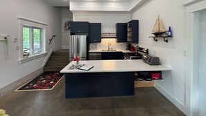 A modern kitchen with dark cabinets, a central island, and a built-in oven. - Welcome to the Lake House (Wiarton)