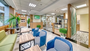 A modern hotel lobby with seating areas, a reception desk, and a TV screen. - Tropica Inn Hotel (Yerevan)