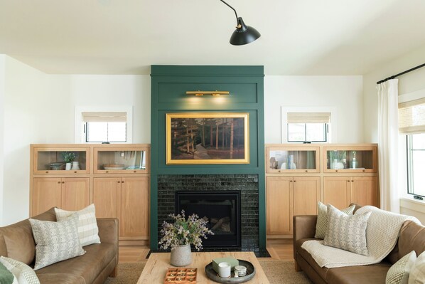 Una sala de estar con chimenea, dos sofás, una mesa de centro y armarios de madera.