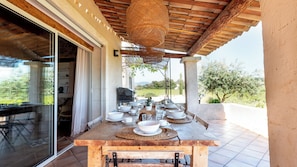 Enjoy a meal under the shade of a pergola with a view of the lush landscape.