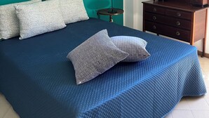 A bedroom with teal walls, a bed with a blue quilt, and a wooden dresser with a mirror.