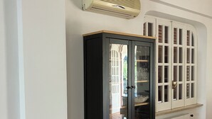 A room with a black cabinet with glass doors, a white radiator, and a white ceiling with an air conditioning unit.
