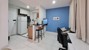 A compact living space with a kitchenette, a dining area with a table and chairs, and a seating area with a sofa. - Lazer Proximo av. Paulista (Bela Vista São Paulo)