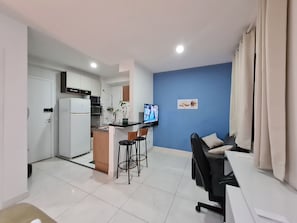 Un espace de vie compact comprenant un coin cuisine, un espace repas avec une table et des chaises, et un coin salon avec un canapé.