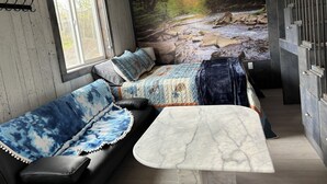 Ett mysigt rum med en säng, ett litet bord och ett fönster med utsikt över en skog.