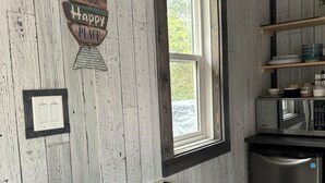 Ett kök med träpanel på väggarna, ett fönster, en vit luftkonditioneringsanläggning och en diskmaskin i rostfritt stål.