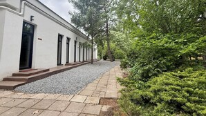 Un edificio con fachada blanca, un sendero de grava y una fila de ventanas.