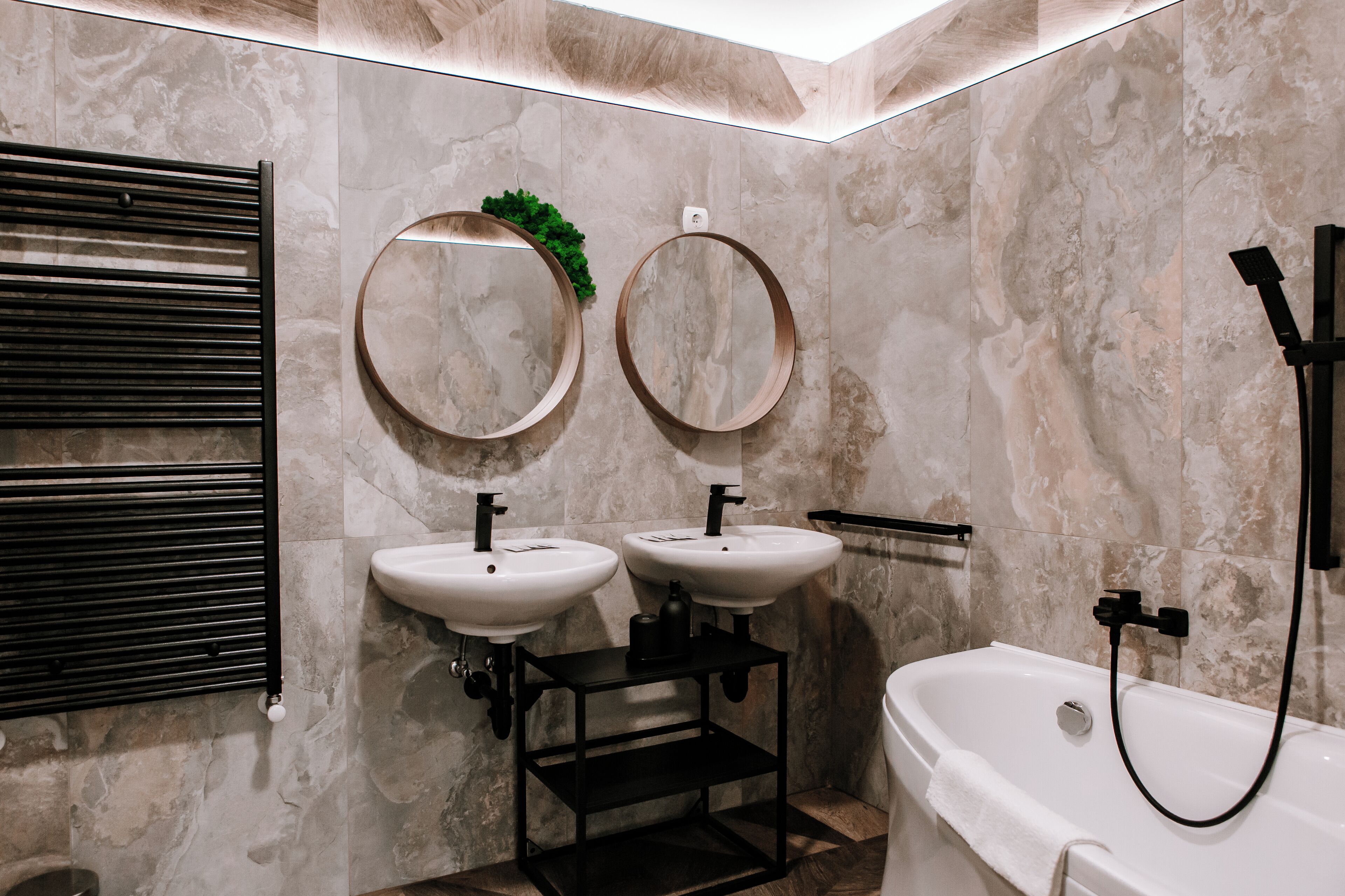 A bathroom with two sinks, a bathtub, and a towel rack.