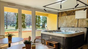 Un jacuzzi con vista a un jardín, una mesa con sillas y un banco.