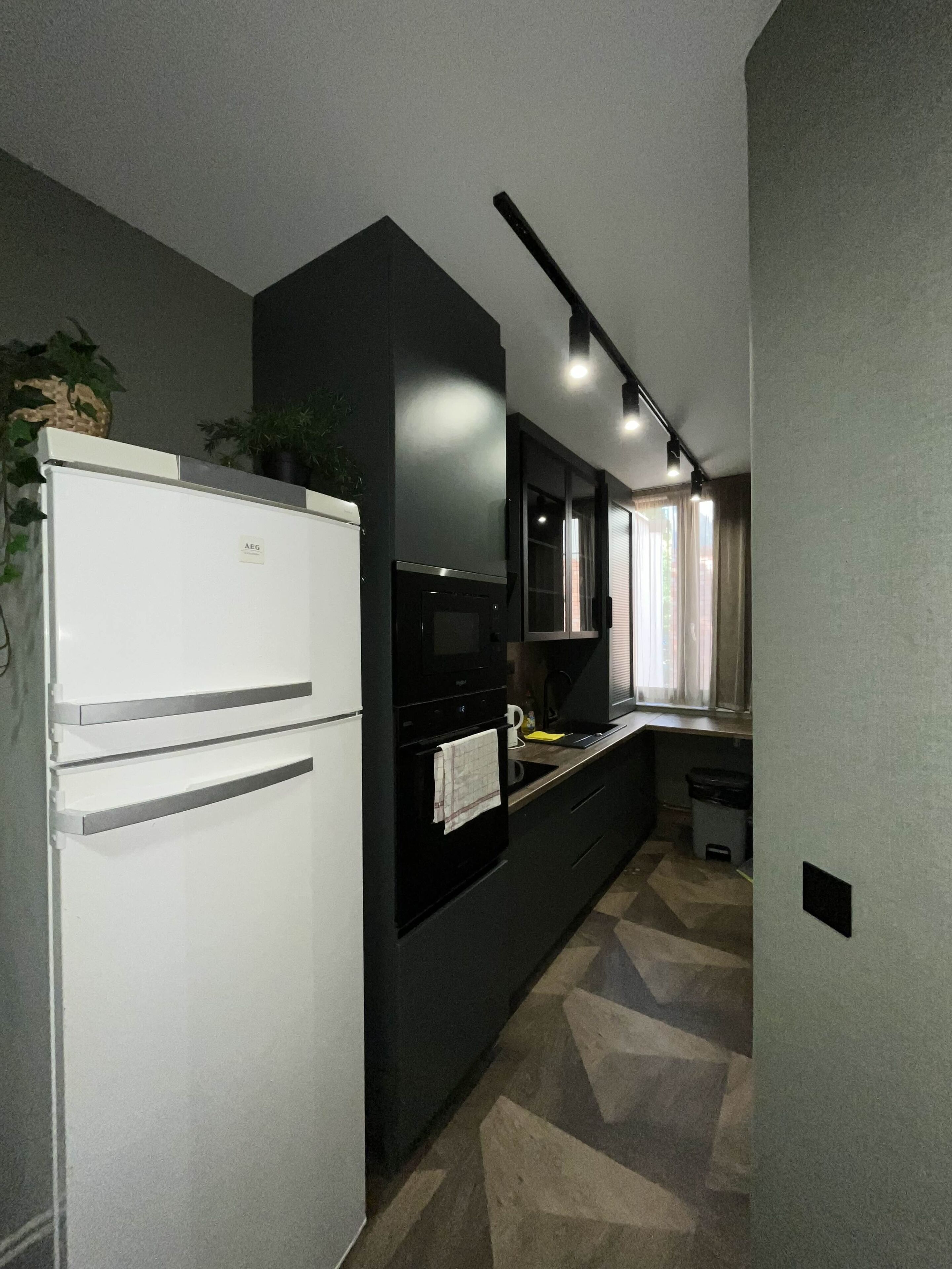 A modern kitchen with a white refrigerator, black cabinetry, and a patterned floor.