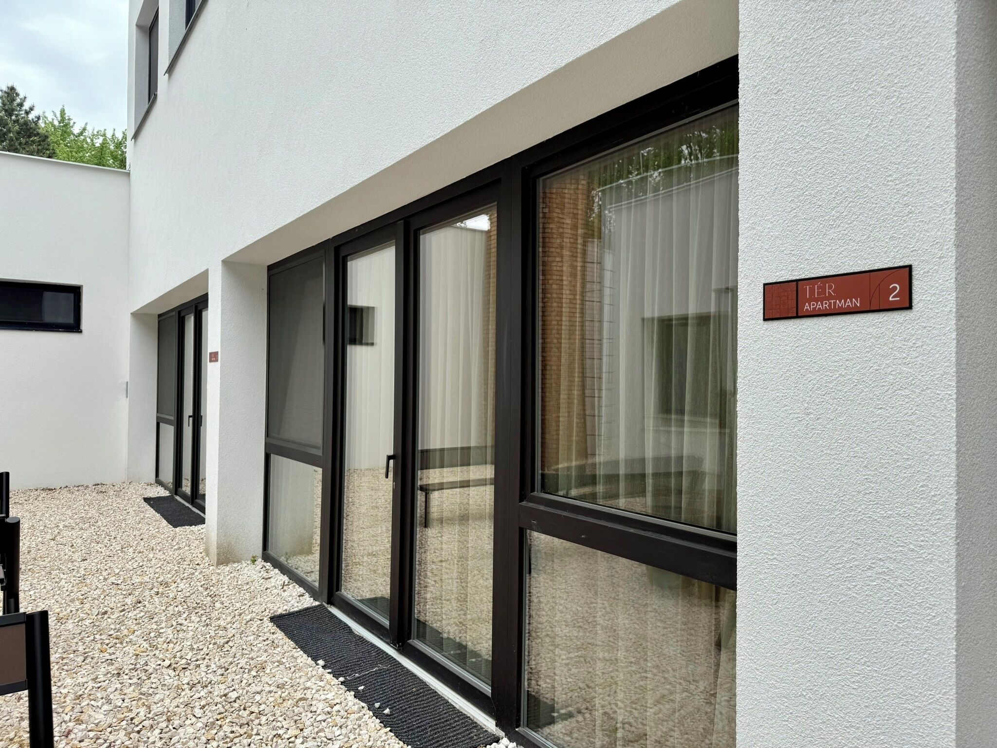 Een modern gebouw aan de buitenkant, met een bord waarop 'Tér Apartment 2' staat.