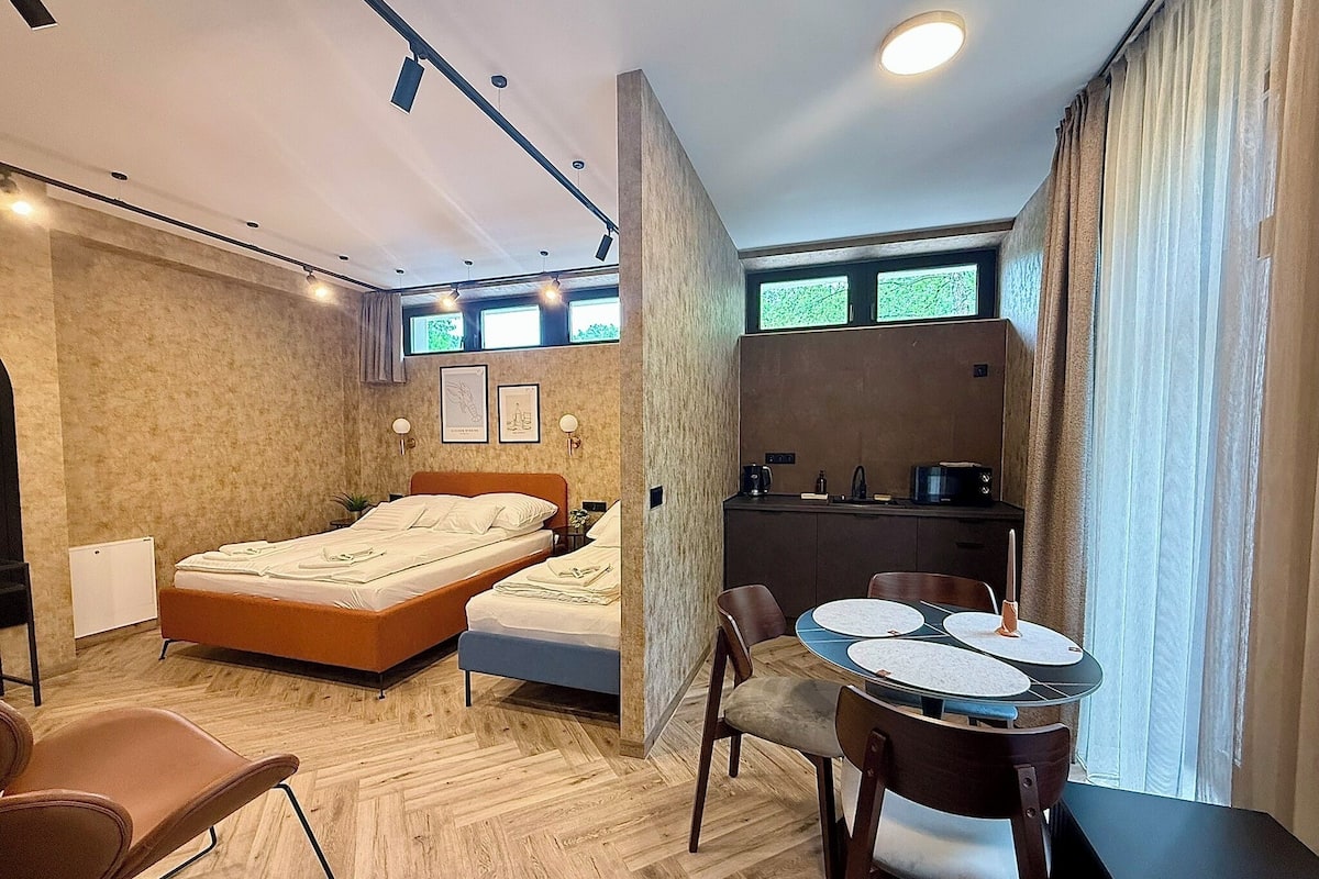 Une chambre avec deux lits, un coin cuisine, un espace repas et une salle de bain.