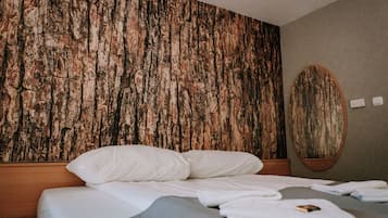 Habitación de hotel con una amplia pared de madera texturizada, una cama con ropa blanca y un espejo redondo en la pared.