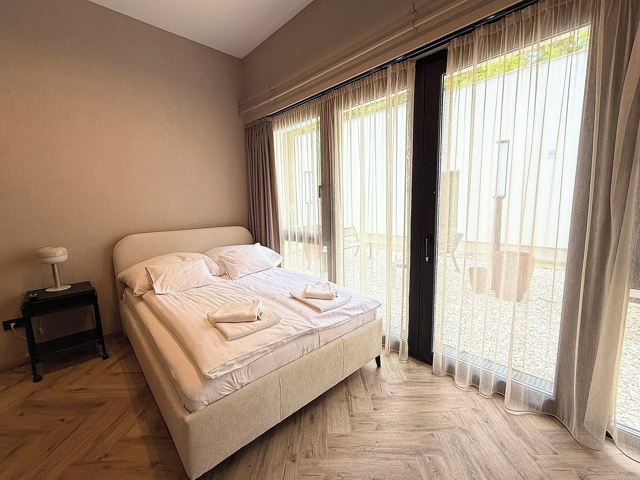 Un dormitorio con cama, mesita de noche y vistas al exterior.