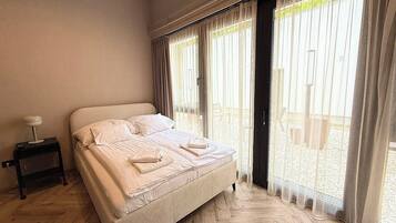 A bedroom with a bed, a nightstand, and a view of the outside.