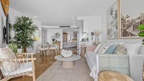 Ein modernes Wohnzimmer mit einer Couch, Sesseln, einem Couchtisch und einem Essbereich.