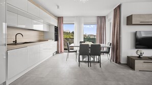 Une cuisine moderne avec des meubles blancs, un plan de travail en bois et un coin repas comprenant une table et des chaises.