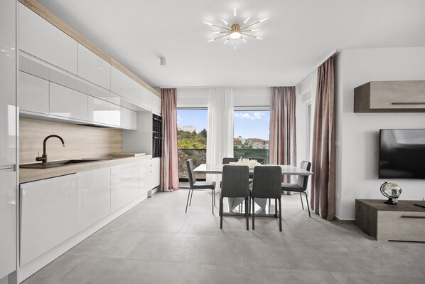A modern kitchen with white cabinets, a wooden countertop, and a dining area with a table and chairs.