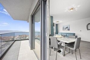 A balcony with a view of buildings, a dining area with a table and chairs, and a ceiling light fixture.