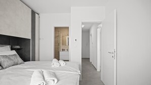 Une chambre d’hôtel moderne avec un lit bien fait, une table de chevet avec une lampe et une vue sur la salle de bain.