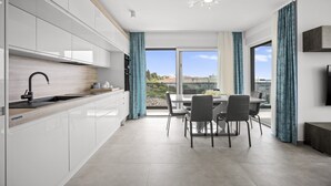 Une cuisine moderne avec des meubles blancs, un plan de travail en bois et un coin repas comprenant une table et des chaises.