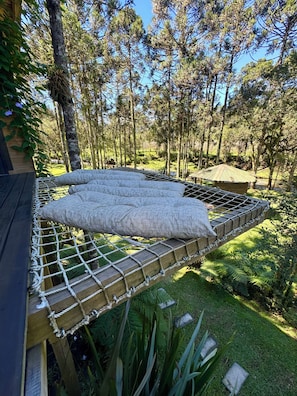 A hammock bed with pillows, set up outdoors with a forest backdrop. - Refuge Green Valley (Urubici)