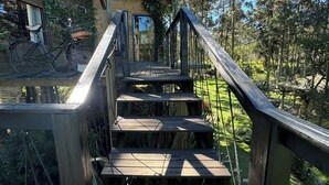 Eine Holztreppe führt zu einer Hütte, die von Bäumen umgeben ist.
