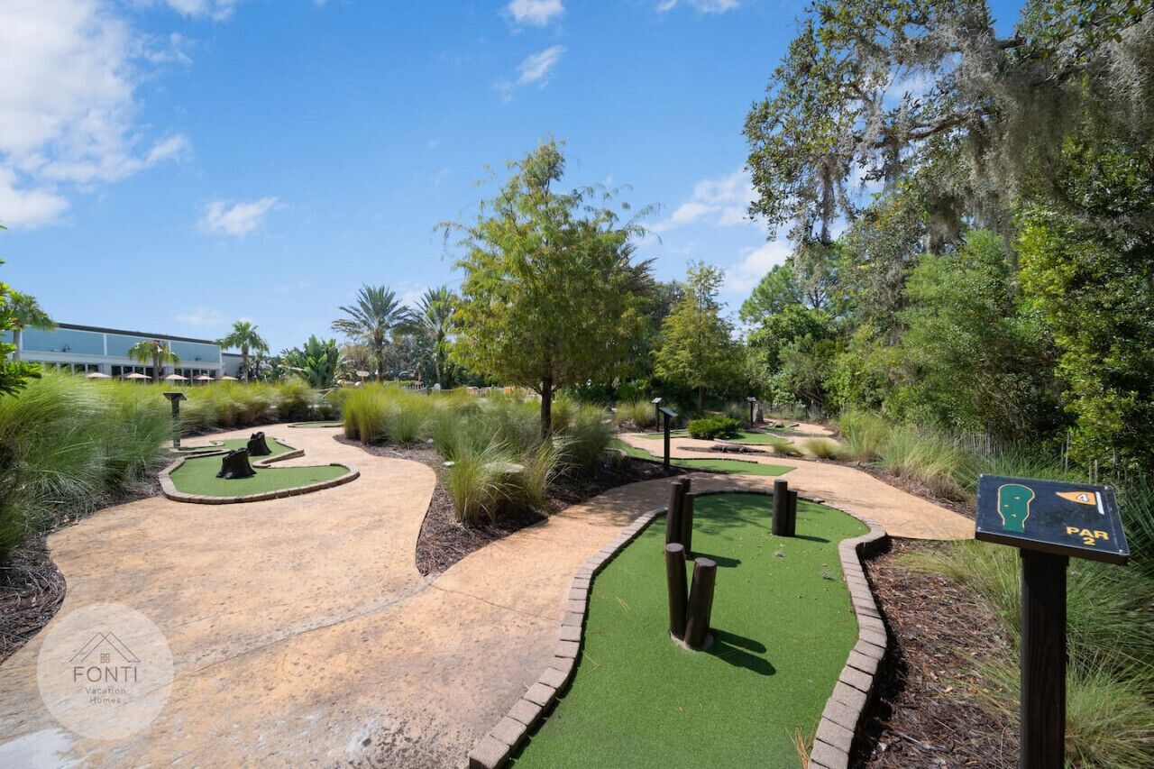 A golf course with a putting green, sand bunkers, and a sign indicating a parking area.