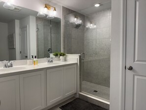 Une salle de bain moderne avec une douche à l’italienne, un grand miroir et un meuble-lavabo blanc.