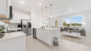 A modern kitchen with white cabinetry, stainless steel appliances, and pendant lighting.