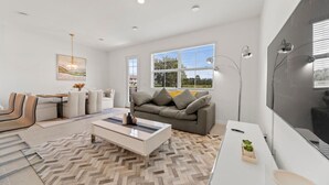 A modern living room with a sofa, coffee table, and a dining area with chairs.