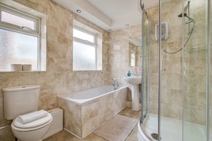 Une salle de bain moderne équipée d’une baignoire, de toilettes et d’un espace douche.