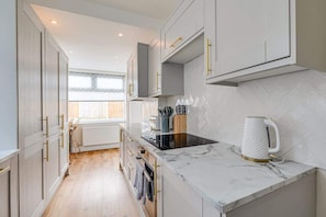 A modern kitchen with white cabinets, a black stove, and a marble countertop.