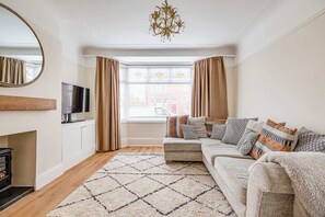 A living room with a sofa, a TV, a fireplace, and a window with curtains.