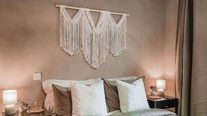 A bedroom with a bed, bedside tables, a macrame wall hanging, and a hanging light fixture. - Stylish 1Bed Apartment in Sheffield CC (Sheffield)