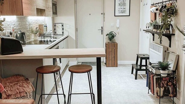 A modern kitchen with bar stools, a dining table, and a coffee machine. - Stylish 1Bed Apartment in Sheffield CC (Sheffield)