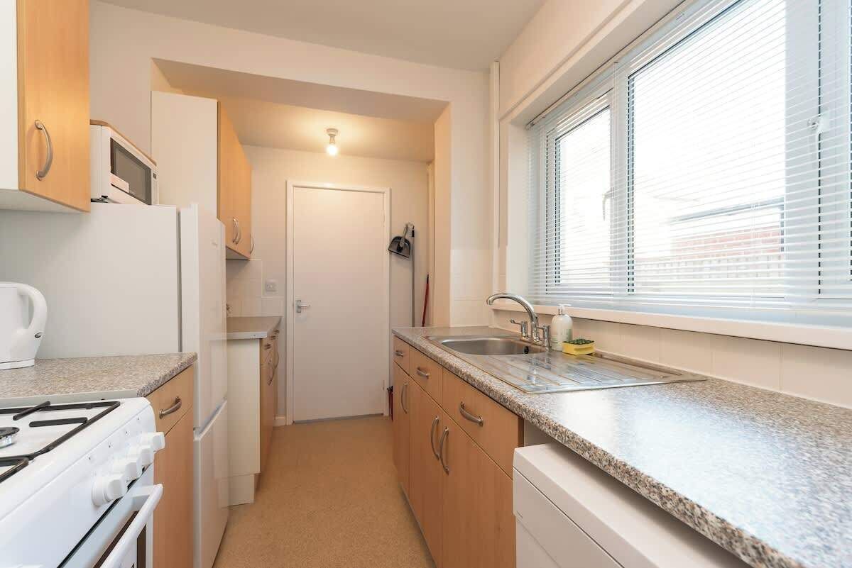 A compact kitchen with a stove, microwave, sink, and cabinets.