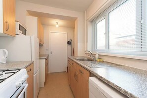 A compact kitchen with a stove, microwave, sink, and cabinets. - Stylish 3BR House in Hull - Sleeps 5 (Hull)