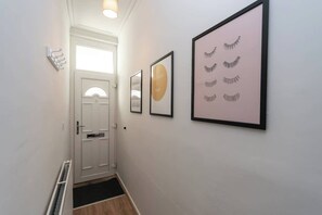 A hallway with a white door, framed artwork, and a radiator. - Stylish 3BR House in Hull - Sleeps 5 (Hull)