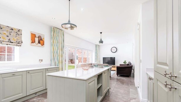 A modern kitchen with a central island, light-colored cabinets, and a large window. - Beautiful Big Family Home: Sleeps 10, Park 3 Cars! (Leeds)