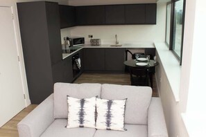 Una cocina moderna con armarios oscuros, un microondas y un comedor con mesa y sillas.
