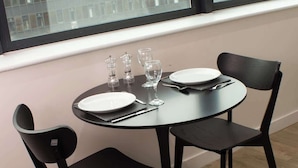 Una mesa de comedor con cuatro sillas, un plato, un vaso y cubiertos.