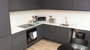 Una cocina moderna con armarios grises, una encimera blanca, un microondas, un tostador y un lavavajillas.