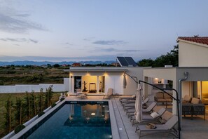 Une maison moderne dotée d’une piscine, d’un espace salon extérieur et offrant une vue sur les montagnes.