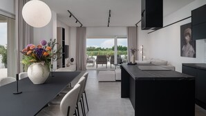 Eine moderne Küche mit Essbereich, großen Fenstern und Blick auf Grünfläche.