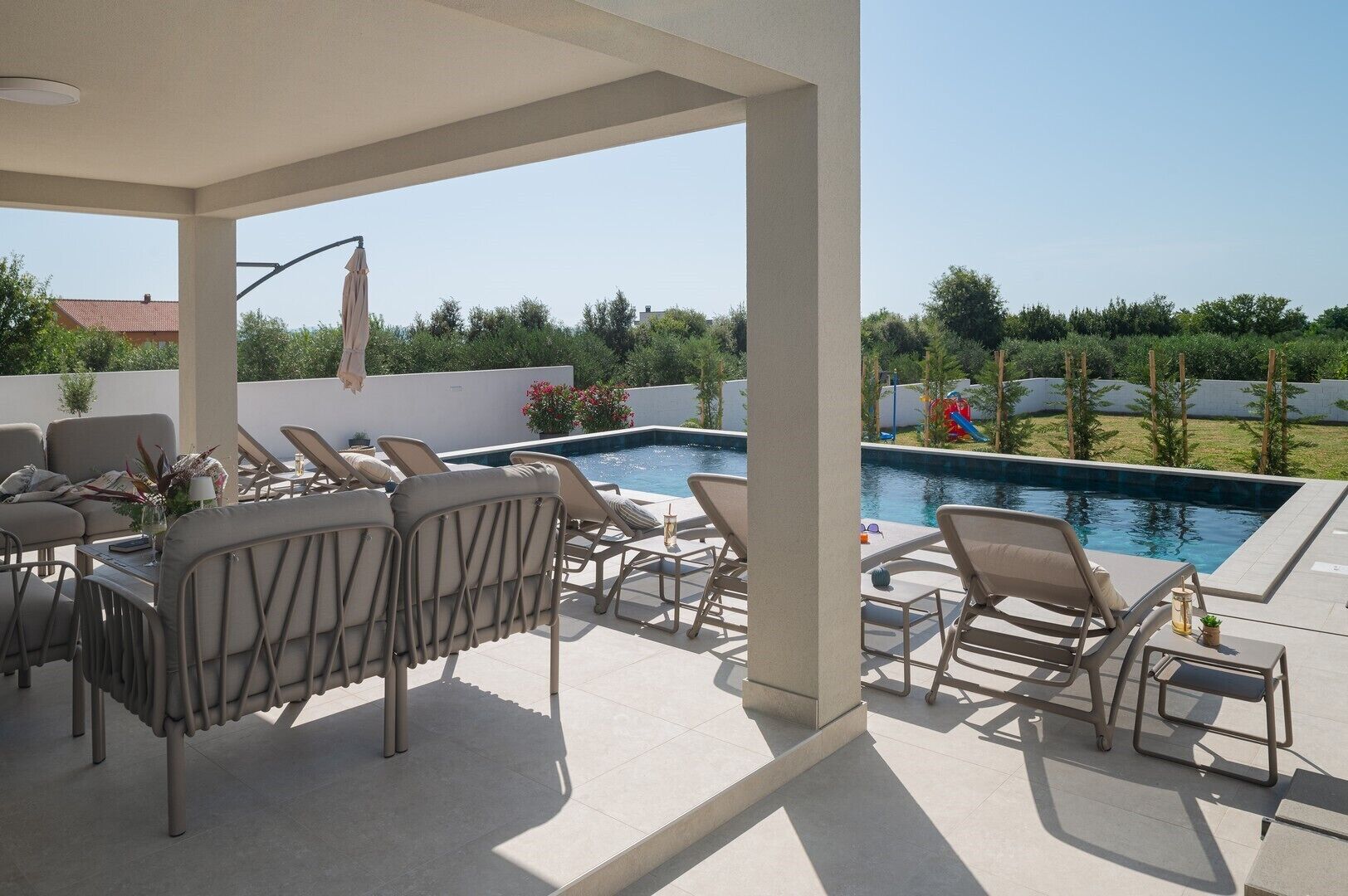 An outdoor pool area with lounge chairs and a covered seating area.